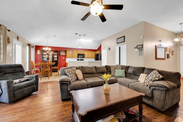 living area with a chandelier, lofted ceiling, light wood-style floors, and ceiling fan