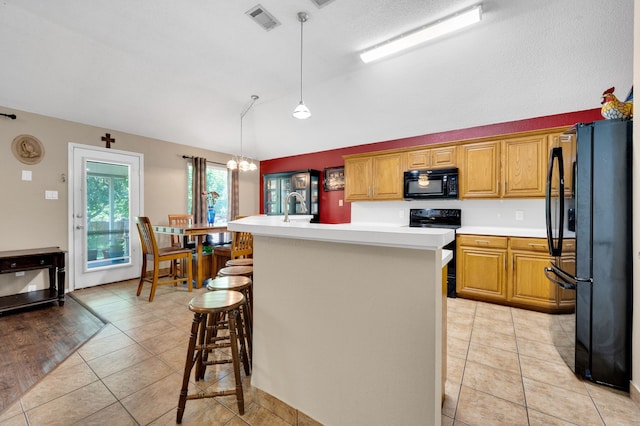 kitchen with black appliances, light countertops, a kitchen island with sink, a kitchen bar, and a sink