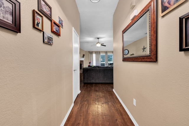 hallway featuring dark wood finished floors and baseboards