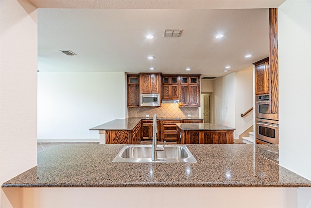 15097 Blakehill Dr, Frisco, TX 75035 - kitchen featuring a sink, stainless steel appliances, glass insert cabinets, a peninsula, and recessed lighting
