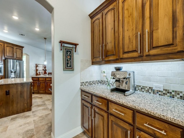 1141 Saint Peter Ln, Prosper, TX 75078 - kitchen with stainless steel fridge with ice dispenser, arched walkways, backsplash, light stone counters, and recessed lighting