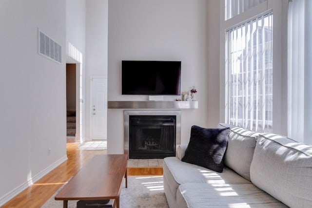 3100 Cole Ave Unit 203, Dallas, TX 75204 - living room featuring wood finished floors, a high ceiling, a fireplace with flush hearth, and baseboards
