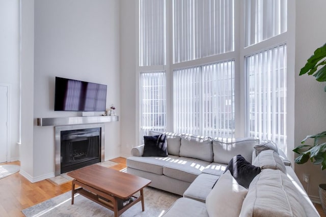 3100 Cole Ave Unit 203, Dallas, TX 75204 - living area featuring healthy amount of natural light, a fireplace with flush hearth, wood finished floors, a high ceiling, and baseboards