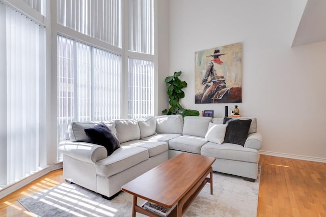 3100 Cole Ave Unit 203, Dallas, TX 75204 - living room featuring light wood-style floors, a high ceiling, and baseboards