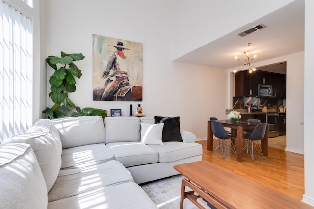 3100 Cole Ave Unit 203, Dallas, TX 75204 - living room with light wood finished floors, baseboards, and a chandelier