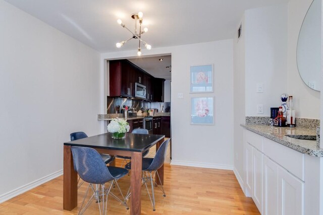 3100 Cole Ave Unit 203, Dallas, TX 75204 - dining area with a chandelier, light wood-style floors, and baseboards