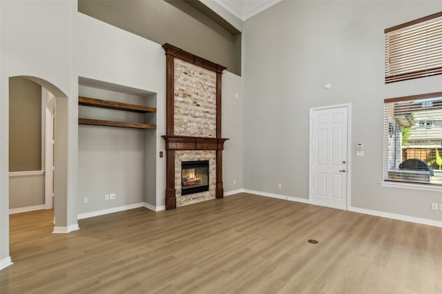 1968 Crowbridge Dr, Frisco, TX 75033 - unfurnished living room featuring light wood finished floors, a towering ceiling, a stone fireplace, and baseboards