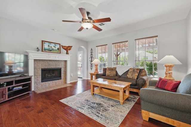 6600 Stewart Blvd, The Colony, TX 75056 - living area featuring ceiling fan, wood finished floors, a tile fireplace, and arched walkways