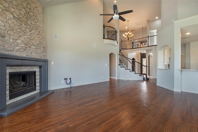 188 Las Colinas Trl, Cross Roads, TX 76227 - unfurnished living room with arched walkways, a glass covered fireplace, a ceiling fan, a towering ceiling, and stairway