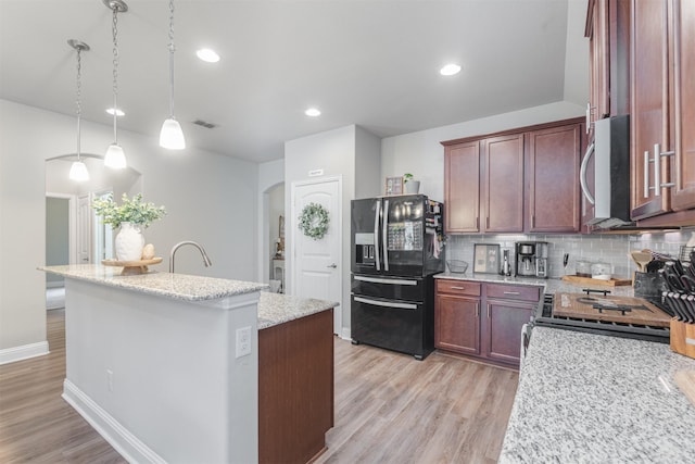 816 Kinghaven Dr, Little Elm, TX 75068 - kitchen with stainless steel appliances, arched walkways, light wood-type flooring, a kitchen island with sink, and recessed lighting