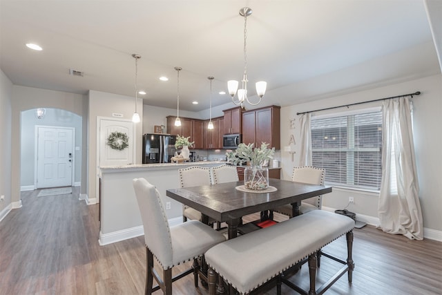 816 Kinghaven Dr, Little Elm, TX 75068 - dining area with arched walkways, light wood-type flooring, baseboards, recessed lighting, and a chandelier