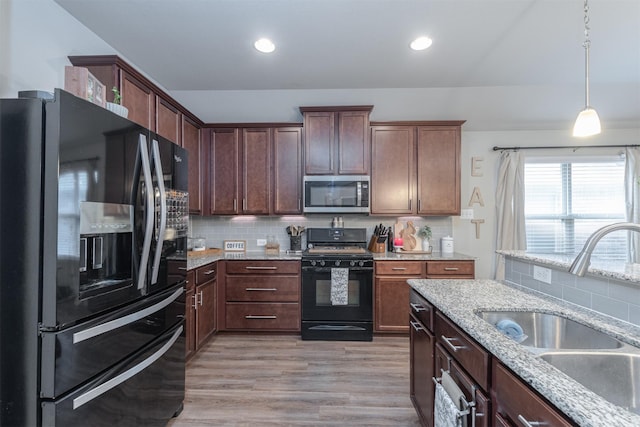 816 Kinghaven Dr, Little Elm, TX 75068 - kitchen with black appliances, a sink, tasteful backsplash, light stone counters, and pendant lighting