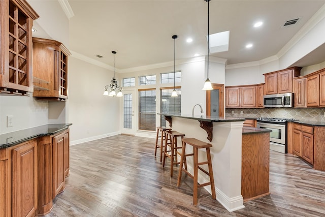2132 Portwood Way, Fort Worth, TX 76179 - kitchen with stainless steel appliances, brown cabinets, a kitchen breakfast bar, ornamental molding, and decorative backsplash