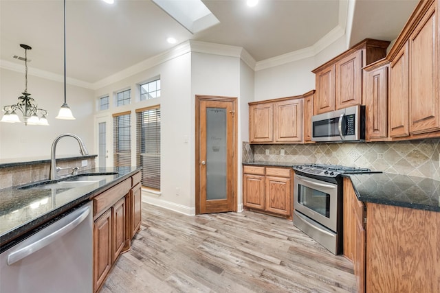 2132 Portwood Way, Fort Worth, TX 76179 - kitchen with appliances with stainless steel finishes, a sink, crown molding, dark stone countertops, and light wood finished floors