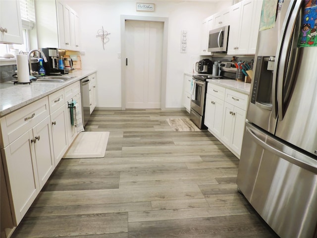 1630 County Road 3239, Hico, TX 76457 - kitchen with stainless steel appliances, a sink, light wood-style flooring, white cabinets, and light stone countertops