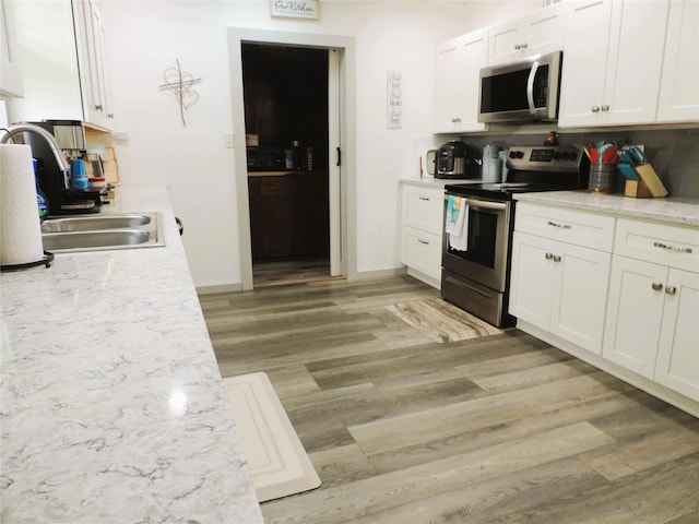 1630 County Road 3239, Hico, TX 76457 - kitchen with stainless steel appliances, light wood-style flooring, white cabinets, a sink, and light stone countertops