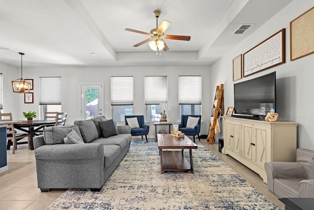 501 Bird Creek Dr, Little Elm, TX 75068 - living room featuring light tile patterned flooring, a ceiling fan, a tray ceiling, and a chandelier
