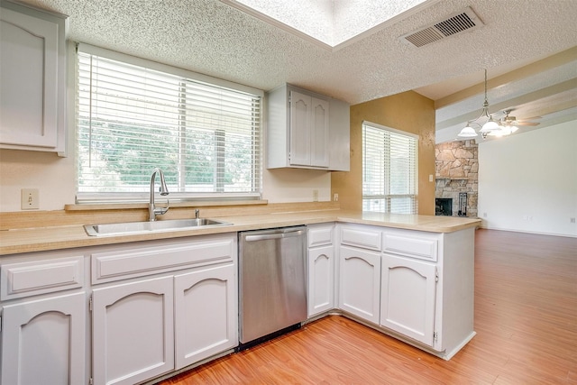 6436 Meadowlark Ln E, Watauga, TX 76148 - kitchen with dishwasher, a sink, a peninsula, a textured ceiling, and light countertops