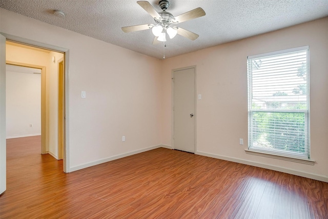 6436 Meadowlark Ln E, Watauga, TX 76148 - empty room with light wood-style flooring, healthy amount of natural light, a ceiling fan, a smoke detector, and a textured ceiling
