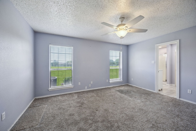 carpeted empty room featuring a ceiling fan, a textured ceiling, and baseboards