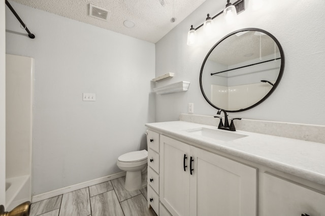 full bathroom featuring toilet, a textured ceiling, vanity, marble finish floors, and baseboards