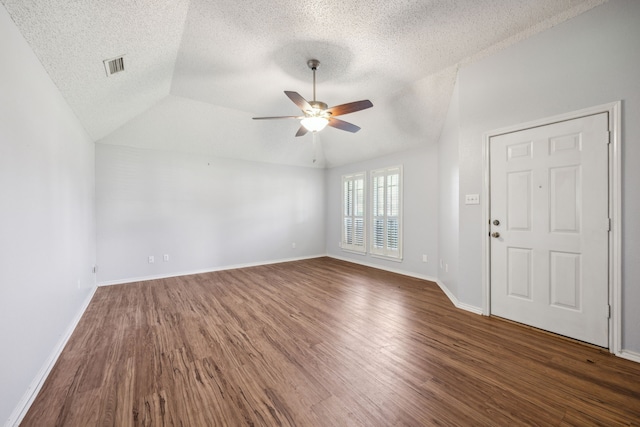 empty room featuring wood finished floors, a textured ceiling, a ceiling fan, baseboards, and vaulted ceiling