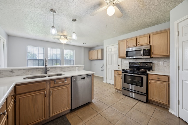 kitchen featuring appliances with stainless steel finishes, a sink, decorative backsplash, a ceiling fan, and a textured ceiling