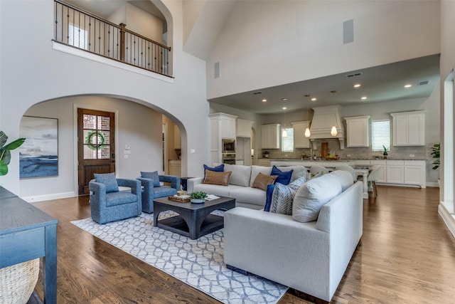 2205 Grafton Ln, Mckinney, TX 75071 - living room featuring wood finished floors, arched walkways, a towering ceiling, and baseboards