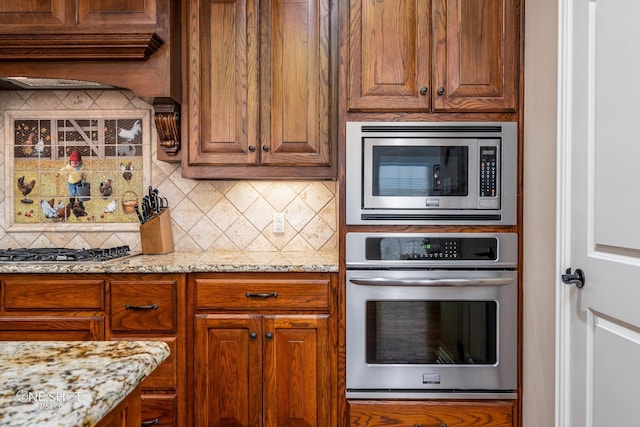 4549 Coyote Run, Abilene, TX 79602 - kitchen featuring stainless steel appliances, decorative backsplash, light stone counters, brown cabinetry, and range hood