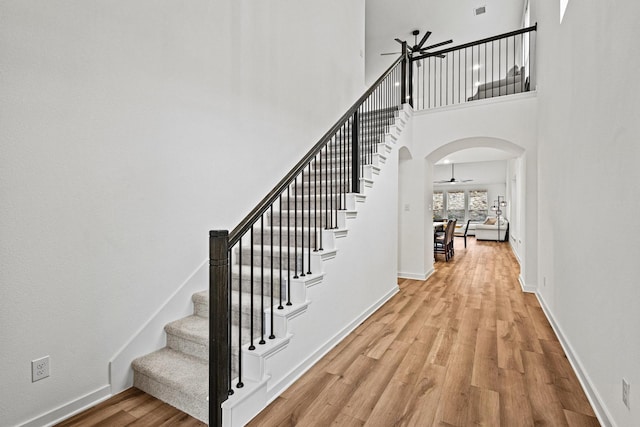 3952 Oak Creek Cir, Denison, TX 75020 - staircase with wood finished floors, a ceiling fan, arched walkways, baseboards, and a high ceiling