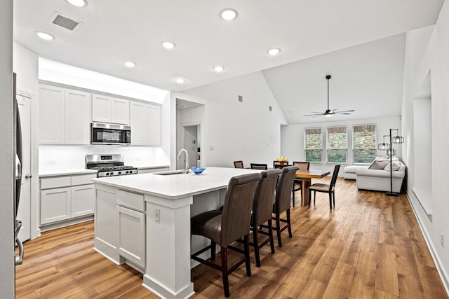 3952 Oak Creek Cir, Denison, TX 75020 - kitchen with appliances with stainless steel finishes, a sink, ceiling fan, vaulted ceiling, and a kitchen breakfast bar