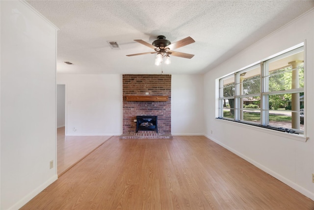 125 Harrison, Detroit, TX 75436 - unfurnished living room featuring a textured ceiling, a ceiling fan, wood finished floors, a brick fireplace, and baseboards