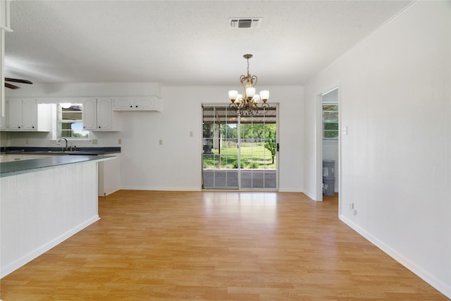 125 Harrison, Detroit, TX 75436 - kitchen featuring a chandelier, dark countertops, light wood-style flooring, a textured ceiling, and decorative light fixtures