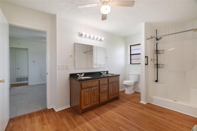 125 Harrison, Detroit, TX 75436 - bathroom featuring a textured ceiling, a shower, wood finished floors, ceiling fan, and toilet