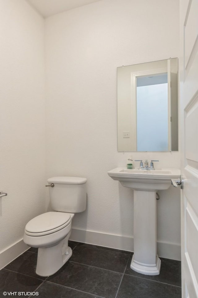bathroom with toilet, baseboards, and tile patterned floors