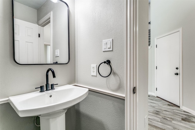 7711 Heather Ridge Ct, Irving, TX 75063 - bathroom with wood finished floors, a sink, baseboards, and a textured wall