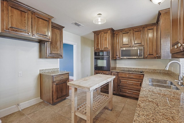 4532 Calmont Ave, Fort Worth, TX 76107 - kitchen featuring black appliances, a sink, light stone counters, and baseboards