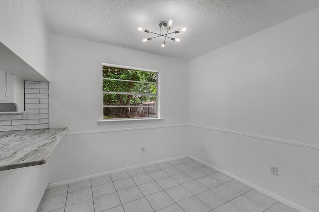 6032 Highcrest Dr, Watauga, TX 76148 - unfurnished dining area featuring a chandelier, a textured ceiling, a wainscoted wall, and light tile patterned flooring