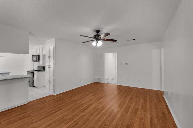 6032 Highcrest Dr, Watauga, TX 76148 - unfurnished living room featuring light wood-style flooring, ceiling fan, a textured ceiling, and baseboards