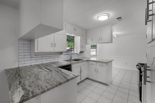 6032 Highcrest Dr, Watauga, TX 76148 - kitchen featuring a sink, a peninsula, a textured ceiling, white cabinetry, and light tile patterned floors
