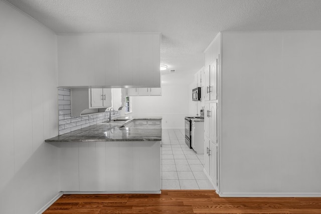 6032 Highcrest Dr, Watauga, TX 76148 - kitchen featuring black electric range, stainless steel microwave, a textured ceiling, a sink, and a peninsula