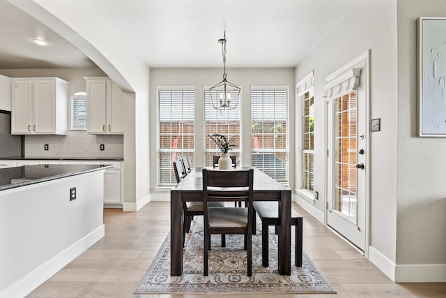 2441 Deerwood Dr, Little Elm, TX 75068 - dining room with baseboards, light wood-type flooring, a chandelier, and arched walkways