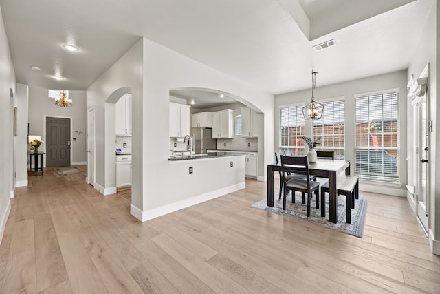 2441 Deerwood Dr, Little Elm, TX 75068 - dining room featuring a chandelier, light wood finished floors, baseboards, and arched walkways