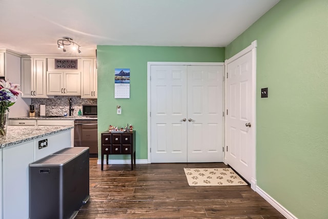 5225 Marks Cir, The Colony, TX 75056 - kitchen with dark wood-type flooring, baseboards, decorative backsplash, light stone counters, and a sink