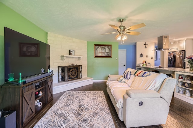 5225 Marks Cir, The Colony, TX 75056 - living room with a ceiling fan, dark wood-type flooring, a stone fireplace, and baseboards