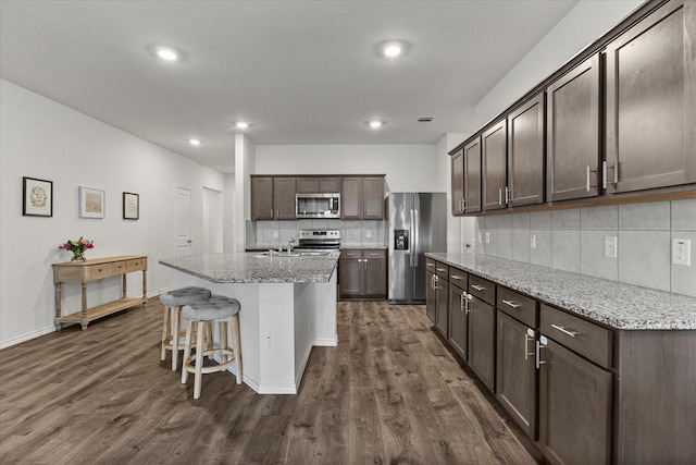 3303 Hawkins Dr, Fate, TX 75189 - kitchen featuring appliances with stainless steel finishes, tasteful backsplash, dark brown cabinetry, dark wood-style floors, and recessed lighting