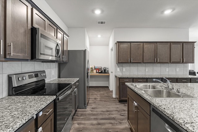 3303 Hawkins Dr, Fate, TX 75189 - kitchen with appliances with stainless steel finishes, a sink, dark brown cabinetry, dark wood-style floors, and backsplash