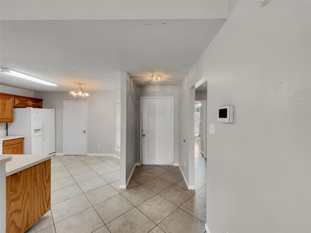 1301 Archdale Ct, Fort Worth, TX 76028 - kitchen with white refrigerator with ice dispenser, light countertops, light tile patterned flooring, a chandelier, and a textured ceiling