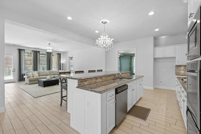 7401 Sabine Dr, Mckinney, TX 75071 - kitchen with stainless steel appliances, a sink, backsplash, an island with sink, and a breakfast bar