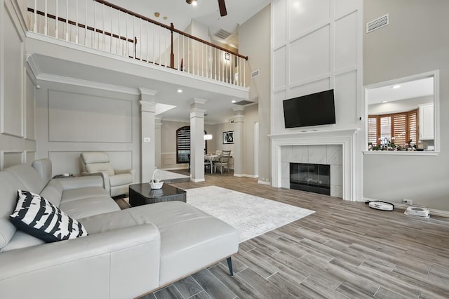 1925 Kiestwood Cir, Plano, TX 75025 - living area with a towering ceiling, decorative columns, a tile fireplace, wood finished floors, and baseboards